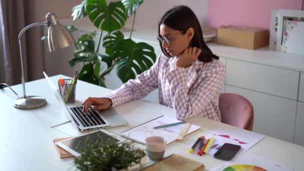 Молодая индийская женщина смешанной расы рассчитывает внутренние счета оплаты кредита онлайн на ноутбуке сидеть за столом офиса — стоковое видео