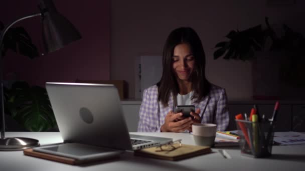 Indian mieszane rasy bizneswoman przeglądanie Internetu przez telefon w godzinach wieczornych w miejscu pracy — Wideo stockowe
