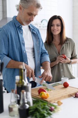 Bir çift evdeki mutfaklarında birlikte yemek pişiriyor..