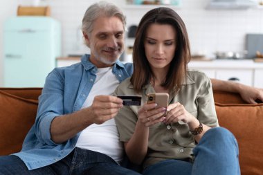 İnternetten alışveriş yapan beyaz bir çift kredi kartından cep telefonu başvurularına ödeme bilgilerini giriyor.