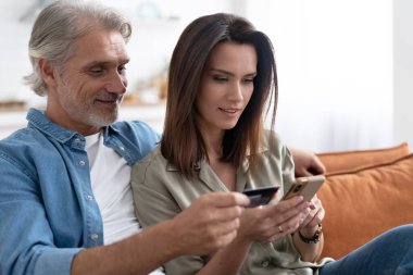 İnternetten alışveriş yapan beyaz bir çift kredi kartından cep telefonu başvurularına ödeme bilgilerini giriyor.