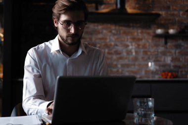Genç başarılı iş adamı kafede otururken dizüstü bilgisayarda çalışıyor.