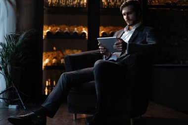 İşadamı gece geç saatlerde kafede otururken tablet bilgisayar kullanarak çalışıyor. Şehre bakan pencerelerin önünde..