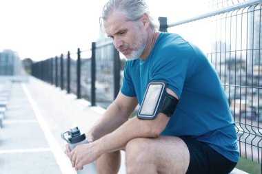 Yorgun Orta yaşlı adam dışarıda koştuktan sonra dinleniyor. Yakışıklı Koşucu Spor yaptıktan sonra mola veriyor