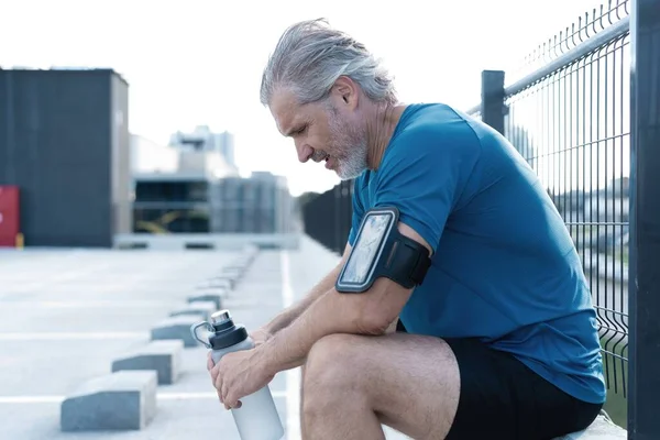 Tired Exhausted Middle-aged Man Resting After Running Outdoors. Handsome Runner Taking Break After Fitness Workout