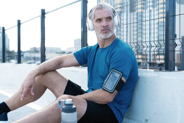 Tired Exhausted Middle-aged Man Resting After Running Outdoors. Handsome Runner Taking Break After Fitness Workout