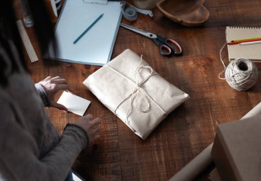 Çalışan kadın iş sahibinin üst düzey görüntüsü, müşteriye nakliye siparişini paketliyor.