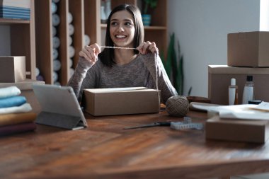 Hintli melez kadın satıcı tablet kullanarak ecommerce giyim mağazasının siparişlerini kontrol ediyor.
