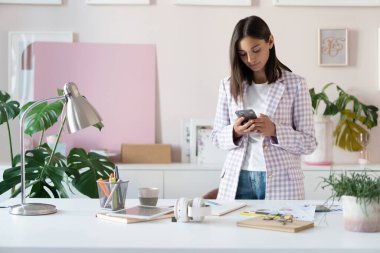 Akıllı telefon mesajları tutan cep telefonu uygulamaları kullanan mutlu Hintli melez genç kadın sosyal medyanın keyfini çıkar