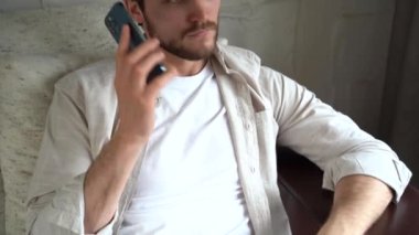 Gülümseyen bir adam birini arıyor, akıllı telefonuyla dinliyor ve konuşuyor.