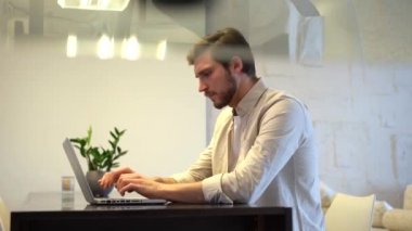 Focused business man entrepreneur typing on laptop doing research, using computer sitting at home office desk