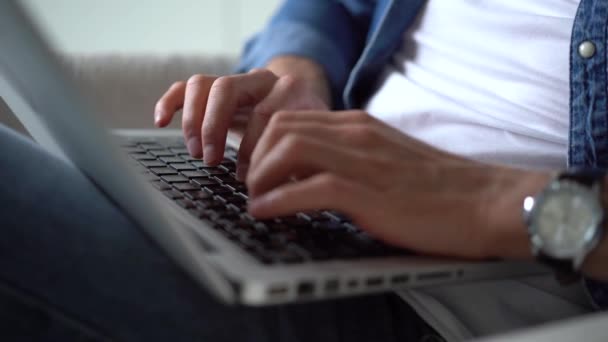 Close-up van mannelijke handen typen op de laptop. Jonge man zit met laptop in de woonkamer, werken Indoor — Stockvideo