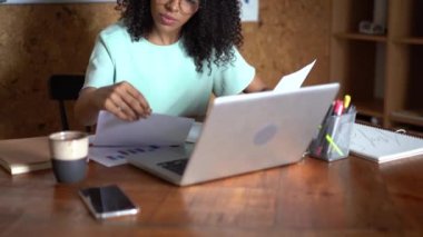 Melez ırktan bir kadın işyerinde oturmuş bilgisayarlı uygulama kullanıyor.