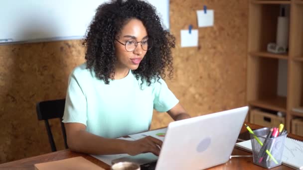 Pensando en la mujer de negocios de raza mixta que trabaja en el ordenador portátil en el interior de la oficina — Vídeo de stock