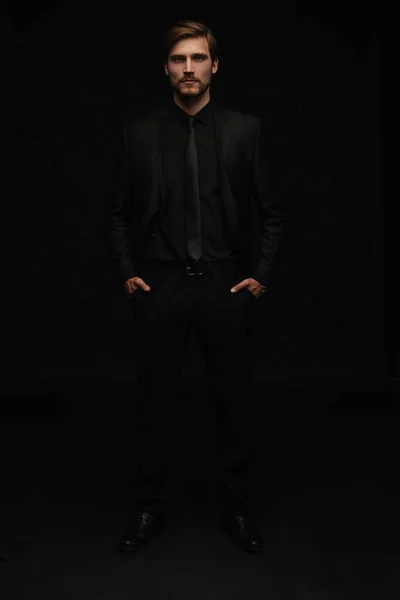 Молодой человек в черном костюме весь портрет тела на черном фоне. — стоковое фото