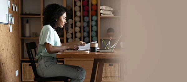 Millennial afroamericana empresaria leyendo papel en su lugar de trabajo en la oficina. — Foto de Stock