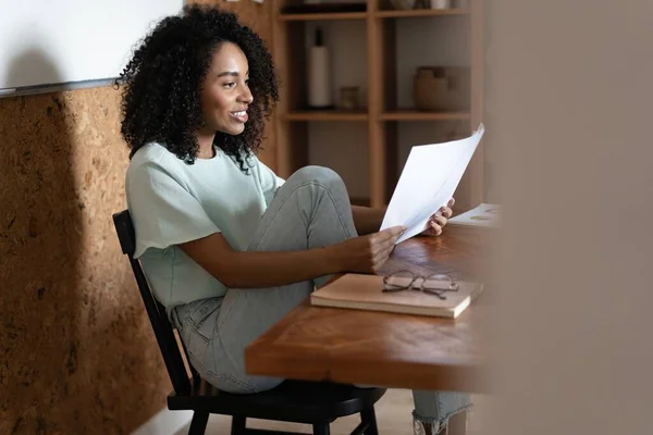Millennial afroamericana empresaria leyendo papel en su lugar de trabajo en la oficina. — Foto de Stock