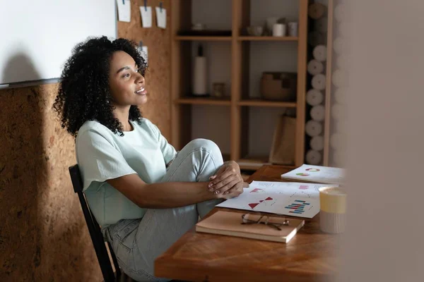 Millennial afroamericana empresaria leyendo papel en su lugar de trabajo en la oficina. — Foto de Stock