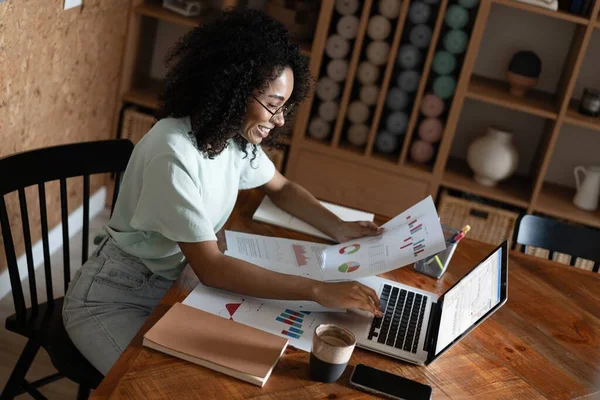 Młoda, piękna, afrykańska kobieta używająca laptopa siedząc na krześle w miejscu pracy — Zdjęcie stockowe