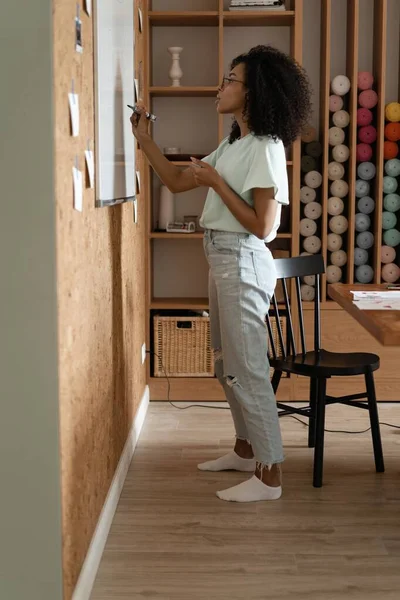 Enfocado joven millennial afroamericana mujer en una ropa casual escribe en el rotafolio en la oficina — Foto de Stock