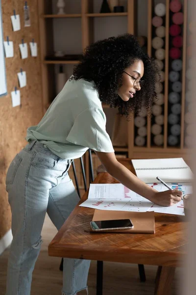 Mujer de negocios hermosa de raza mixta que trabaja con papeles mientras está de pie en la oficina moderna — Foto de Stock