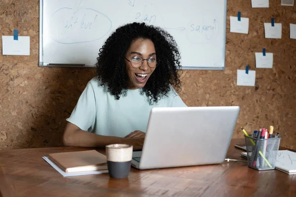 Cheerful mixed race woman laugh using laptop video stream conference call, watch webinar Stock Photo