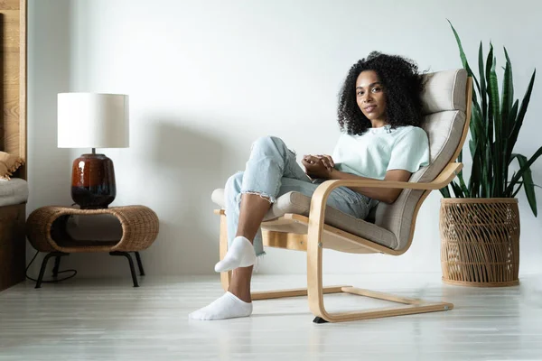 Feliz pacífico africano americano millennial chica sentarse en silla relajarse en casa soñando o visualizando — Foto de Stock