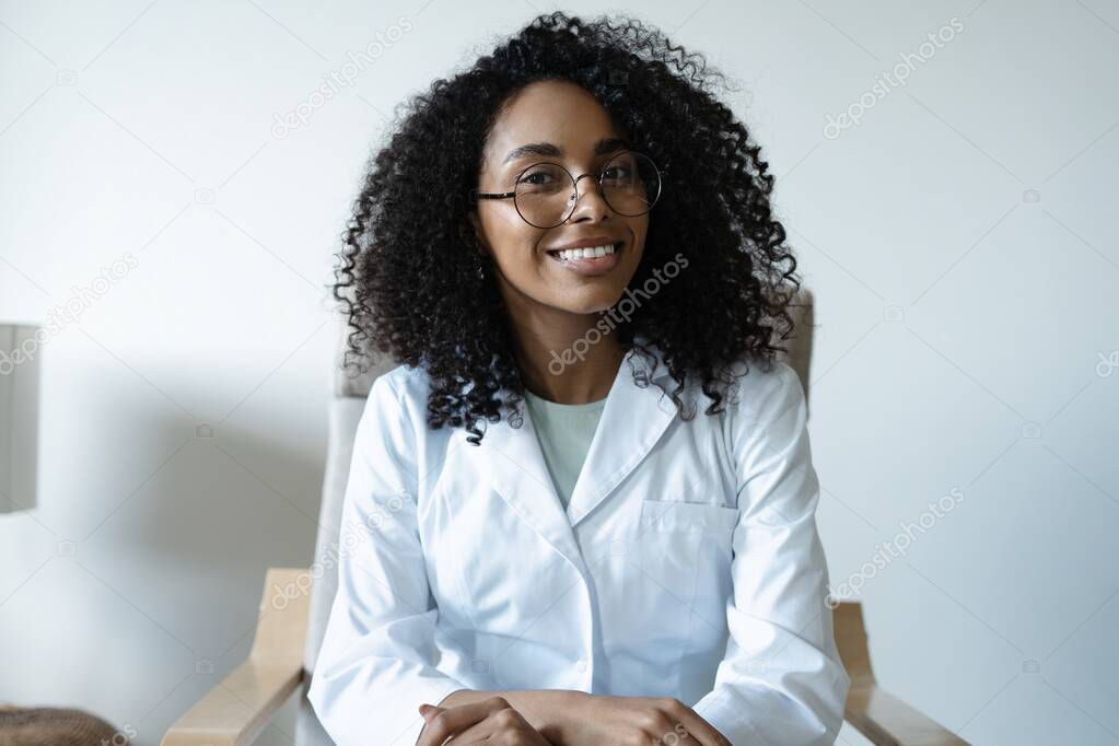 Mixed race woman doctor talking online with patient, making video call, looking at camera