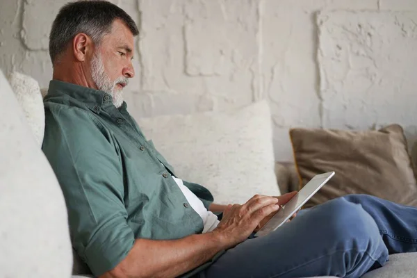 Maduro bonito homem websurf no tablet em casa. — Fotografia de Stock