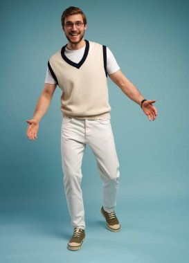 Kameranın önünde poz veren neşeli, sevimli, yakışıklı bir adam. Mavi arka planda soyutlanmış.