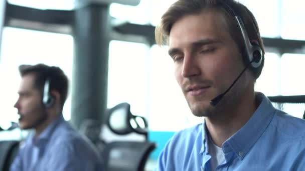 Kablosuz kulaklıklı erkek temsilci çağrı merkezi ajanı müşteri ve müşteri destek servisinde çalışan operatöre yardım ediyor — Stok video