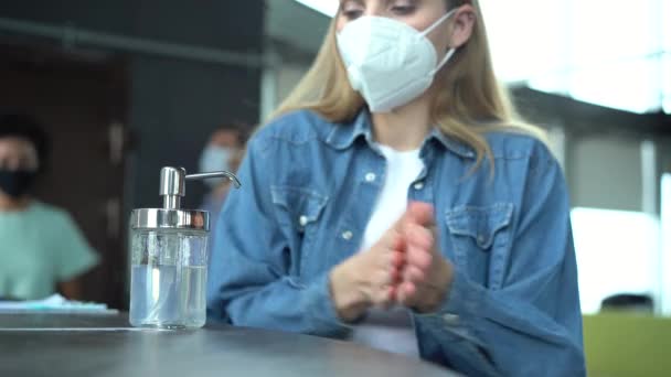 Συνάδελφοι φορώντας προστατευτική μάσκα προσώπου χρησιμοποιώντας απολυμαντικό τζελ αλκοόλ κατά του ιού του στέμματος. — Αρχείο Βίντεο