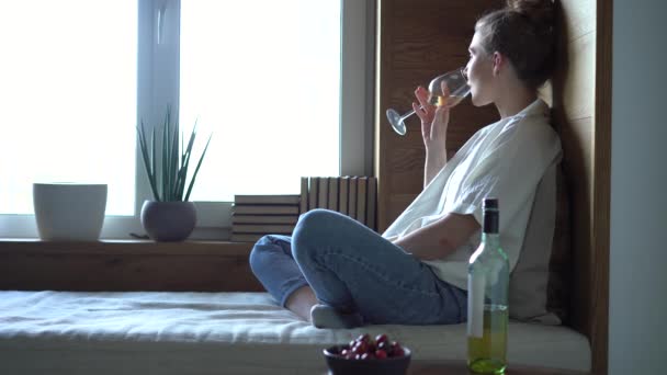 Belle femme relaxante dans un canapé avec un verre de vin tout en se prélassant seule à la maison — Video
