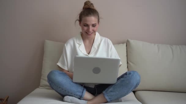 Glad ung kvinna gör videosamtal online chat titta på bärbar skärm sitta på soffan — Stockvideo