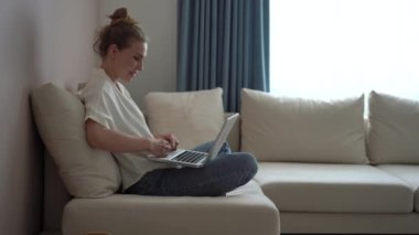 Mutlu genç kadın görüntülü konuşma yapıyor. Laptop ekranına bak. Kanepeye otur.