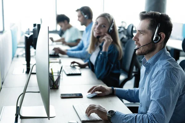 Jonge knappe mannelijke customer support telefoon operator met headset werken in call center — Stockfoto