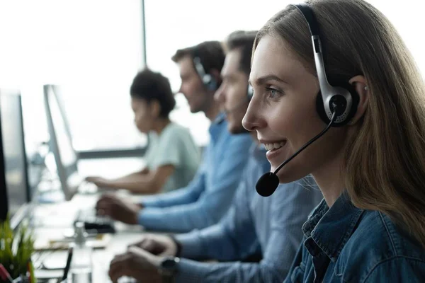 ¿En qué puedo ayudarle? Hermosos trabajadores del centro de llamadas en auriculares están trabajando en la oficina moderna — Foto de Stock