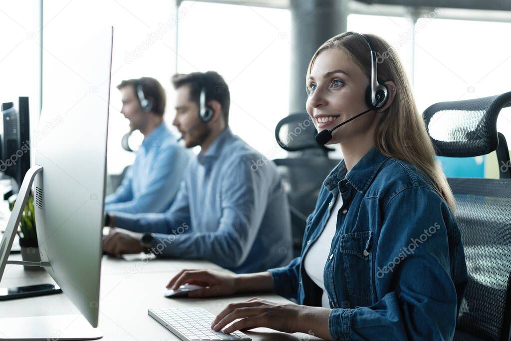 How can I help you. Beautiful call center workers in headphones are working at modern office