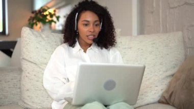 Gülümseyen karışık ırklı kadın videosu iş görüşmesi için evde dizüstü bilgisayar kullanıyor.