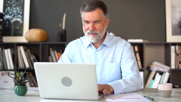 Een serieuze volwassen man werkt met zijn laptop computer op kantoor. — Stockvideo