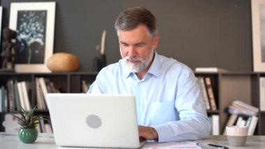 Ofiste dizüstü bilgisayarıyla çalışan çok olgun bir adam..