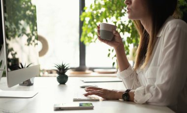 Çağdaş masaüstü bilgisayarını kullanarak ofiste çalışan çekici genç bir kadın..