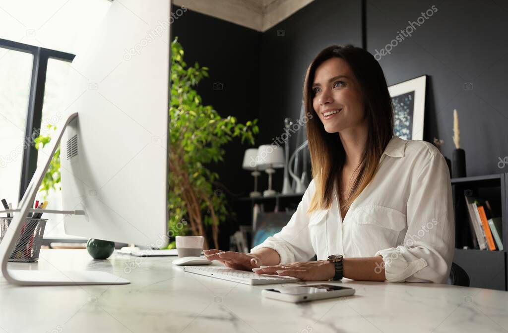 Attractive young woman working at office, using contemporary desktop computer.