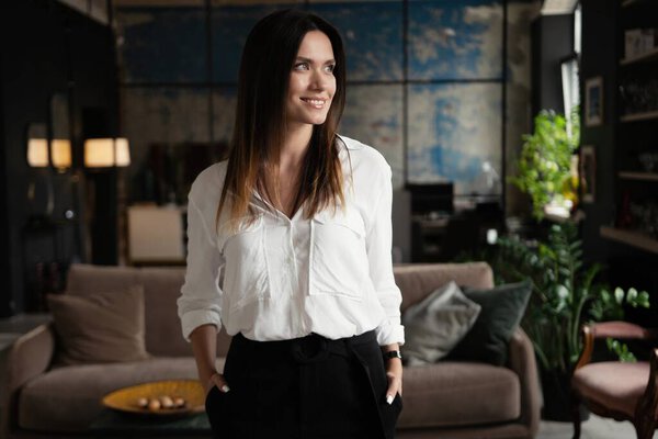 Confident stylish european middle aged woman standing at workplace, 30s lady executive leader manager looking at camera