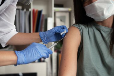 Nüfusu kovid 19 aşısıyla koruma ve aşılama, doktor hastasına bir iğne yapar..