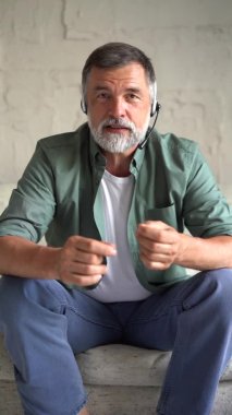 Son sınıf öğrencisinin kameraya bakarken dikey görüntüsü, online öğretmen blogcusu kanepeye oturmuş web kamerasıyla iletişim kuruyor.