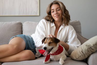 Genç bir kadın ve köpeği evdeki kanepede. Sevimli hayvan..