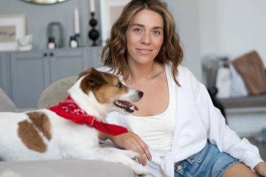 Genç bir kadın ve köpeği evdeki kanepede. Sevimli hayvan..