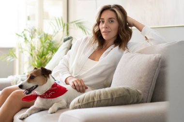 Genç bir kadın ve köpeği evdeki kanepede. Sevimli hayvan..