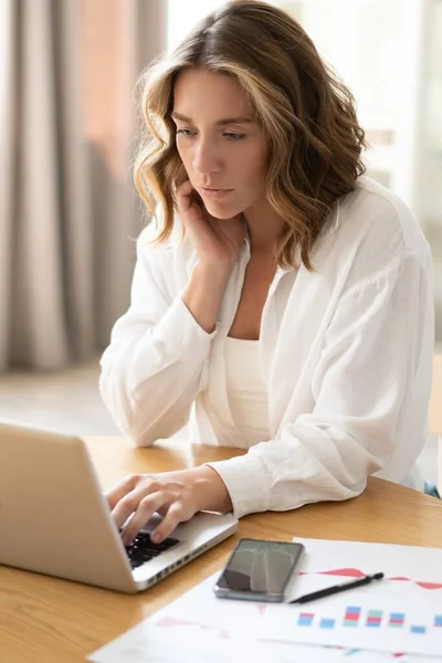 Красива молода жінка працює з дому на ноутбуці . — стокове фото
